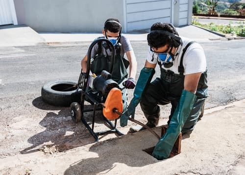 Professionals unblocking sewers on the street sidewalk with steam drain cleaning in edmonton